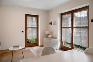 a white living room with a table and two windows at La Casetta Chiesa Valmalenco in Chiesa in Valmalenco