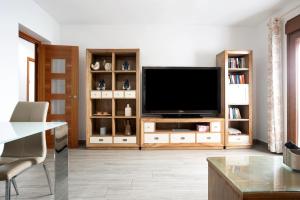 a living room with a television on a wooden entertainment center at Reina's in Vejer de la Frontera