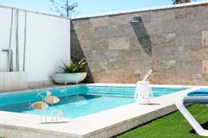 a swimming pool with two chairs next to a house at Casa Orilla Sur B in El Palmar