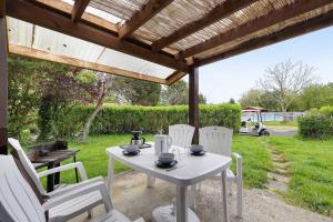 a white table and chairs under a wooden pergola at Chalet confort 20 in Saint-Gervais