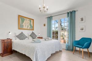 a bedroom with a bed with a blue chair and a window at La Petite Maison Jaune in Grimaud