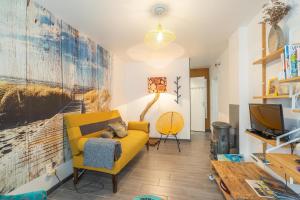 a living room with a yellow couch and a tv at Gite Du Porche Bis in Chaillevette