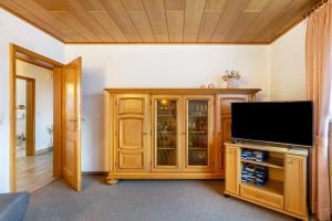 a living room with a television and a wooden cabinet at Ferienwohnung Tannenberg in Diemelstadt 