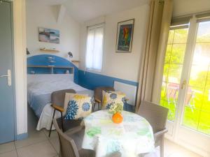 a bedroom with a bed and a table and chairs at Petit Gîte Douillet L'abri Côtier in Saint-Léonard