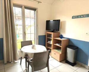 a dining room with a table and a tv at Petit Gîte Douillet L'abri Côtier in Saint-Léonard