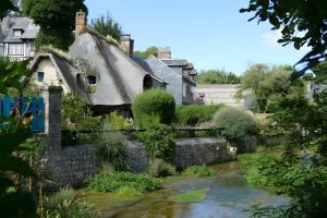 an old house with a thatched roof and a garden at Petit Gîte Douillet L'abri Côtier in Saint-Léonard