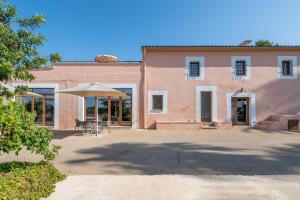 a pink building with a table and an umbrella at Son Guillem in Son Sardina