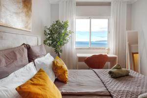 a bedroom with a bed with yellow pillows and a window at Ti Clara View Apartment in Caniço