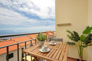 a wooden table on a balcony with a view at Ti Clara View Apartment in Caniço