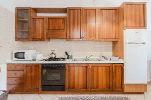 a kitchen with wooden cabinets and a sink and a microwave at Ardesia Vacanze in Valderice +22 photos