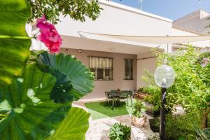 a garden with a table and a pink flower at Ardesia Vacanze in Valderice