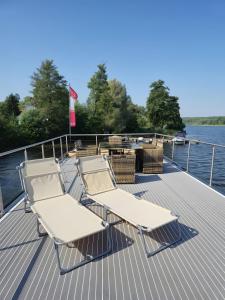 two lounge chairs and a table on the deck of a boat at Gemütliches Hausboot Aquila Woma in Fürstenberg