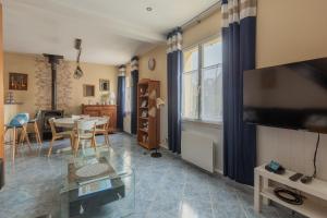 a living room with a tv and a table with chairs at Maison maxi 8 personnes, proche mer in Mers-les-Bains