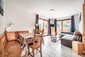 a living room with a table and a couch at Appart 6 pers – Accès direct Ski in Morillon
