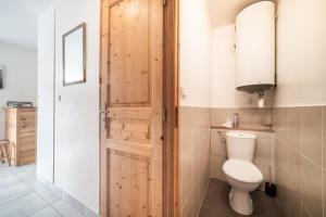 a bathroom with a toilet and a wooden door at Appart 6 pers – Accès direct Ski in Morillon +13 photos