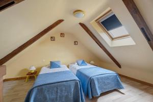 two beds in a attic room with a window at Gite Hirondelle in Lanvallay