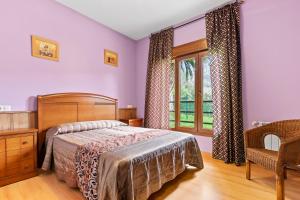 a bedroom with a bed and a window and a chair at Apartamentos Les Cuartes in Cangas de Onís