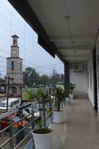 a building with a clock tower in a parking lot at Hotel Golden Mahseer in Tezu