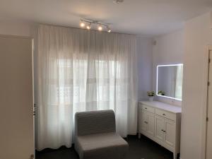 a bedroom with a window with a chair and a dresser at Beach Bungalow in Torrox
