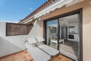 a balcony with a white chair and a kitchen at Oasis del Sur in San Miguel de Abona