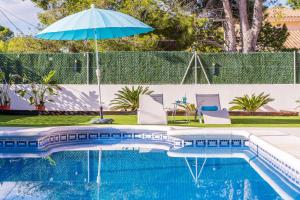 a swimming pool with a blue umbrella and chairs at Las Palmeras in Tarragona
