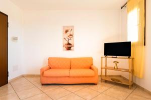 an orange chair in a living room with a tv at Casa Manuela in Lecce