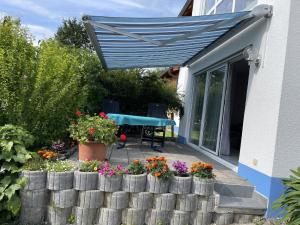 a blue canopy over a patio with flowers and a table at Ferienwohnung - Haus Waibel in Überlingen