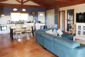 a living room with a blue couch and a kitchen at Le Gite De La Colline in Nérac