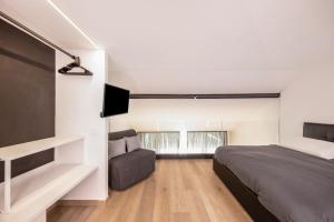 a bedroom with a bed and a couch and a tv at Appartamento Mazzin in Mazzin