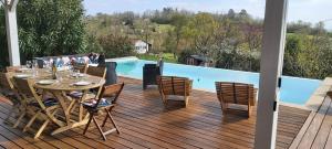 a deck with a table and chairs and a pool at Le Gite De La Colline in Nérac