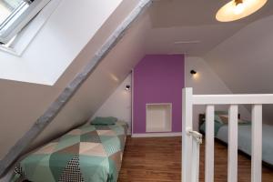 a attic bedroom with purple walls and a bunk bed at Petite Maison Malestroyenne in Malestroit