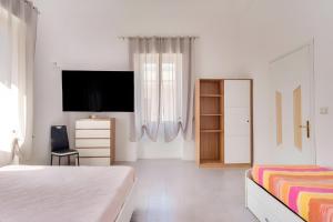 a white bedroom with a tv and a bed at Suite Biancolino in Nardò