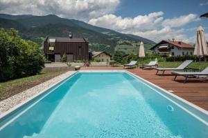 a swimming pool with a house and mountains in the background at Sommersbergerhof 1968 in Bressanone