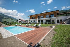 a house with a wooden deck and a swimming pool at Sommersbergerhof 1968 in Bressanone