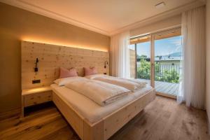 a bedroom with a large bed and a large window at Sommersbergerhof 1968 in Bressanone +17 photos