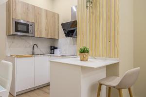 a kitchen with white cabinets and a microwave and a chair at Apartamentos Brisas de Cádiz 3 in Cádiz +15 photos