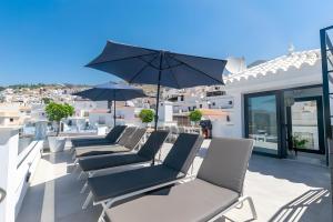 a row of chairs on a balcony with an umbrella at Stunning apartment in Cómpeta in Cómpeta