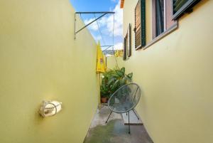 a small alley with a chair and a yellow wall at Levada Residence in Funchal