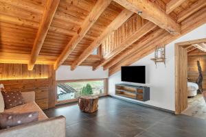 a living room with wooden ceilings and a flat screen tv at Lòni Lodge Vermiglio in Vermiglio