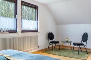 two chairs in a bedroom with a table and two windows at Fewo Naturblick in Wiesenthau +14 photos