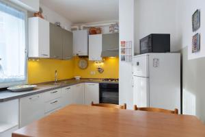 a kitchen with a wooden table and a white refrigerator at La Casetta Gialla in Pieve di Cadore