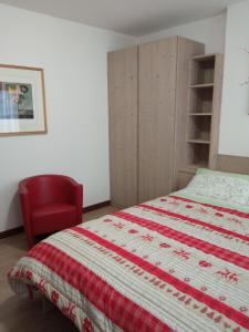 a bedroom with a bed and a red chair at La Casetta Gialla in Pieve di Cadore