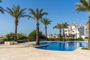 a swimming pool with palm trees and buildings at Casa verde in Roldán