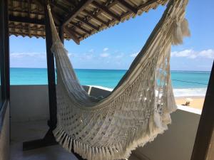 a hammock in a room with a view of the beach at Pousada Maracabana Spa in Porto De Galinhas