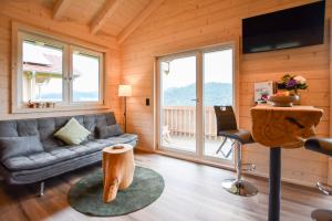 a living room with a couch and a table with a chair at Panoramahisli 3 in Fischerbach