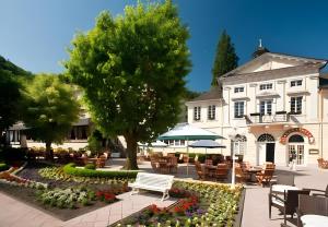 a building with a park with a bench and flowers at Ferienwohnung Auszeit in Bad Bertrich