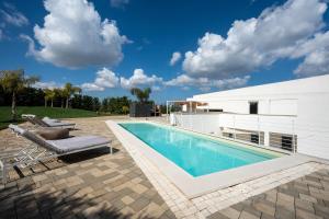 a swimming pool next to a white house at Villa Nilde in Triggianello