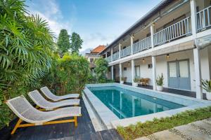 two chairs and a swimming pool next to a building at The Peacock Inn in Ubud