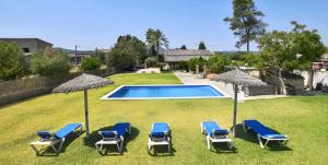 a yard with a swimming pool with chairs and umbrellas at Valls in Montuiri