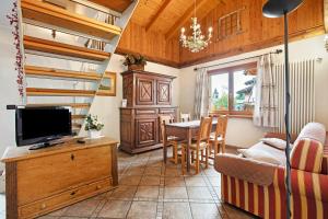 a living room with a television and a dining room at Au Petit Chevrot - Garden in Aosta
